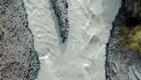 Drone-top-down-dolly---Stuðlagil-canyon,-flowing-glacial-river,-rock-formations