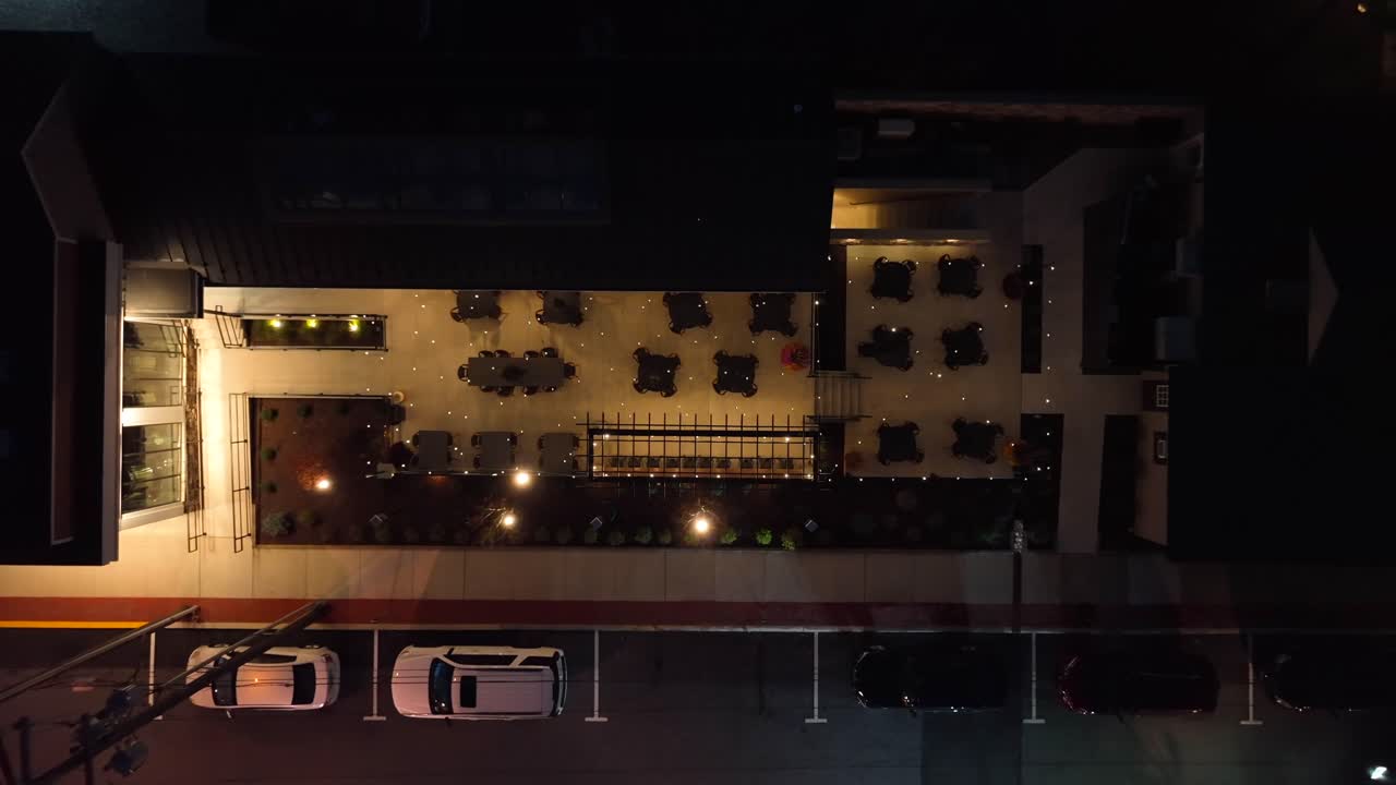 vista aérea de un restaurante en la azotea con asientos al aire libre iluminados por la noche
