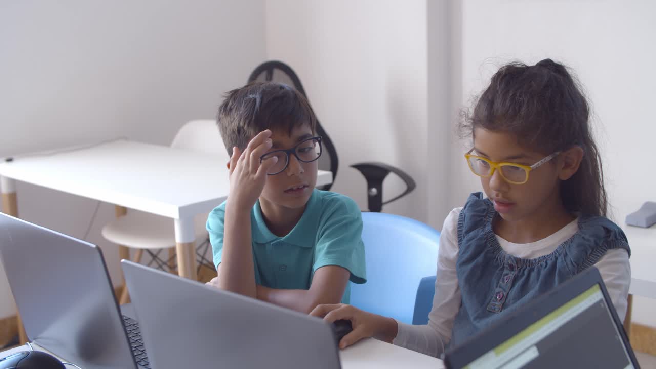 dos compañeros de clase emocionados con gafas colaborando en un proyecto