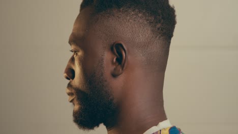 retrato de cerca de un joven afroamericano barbudo girando la cabeza y mirando a la cámara