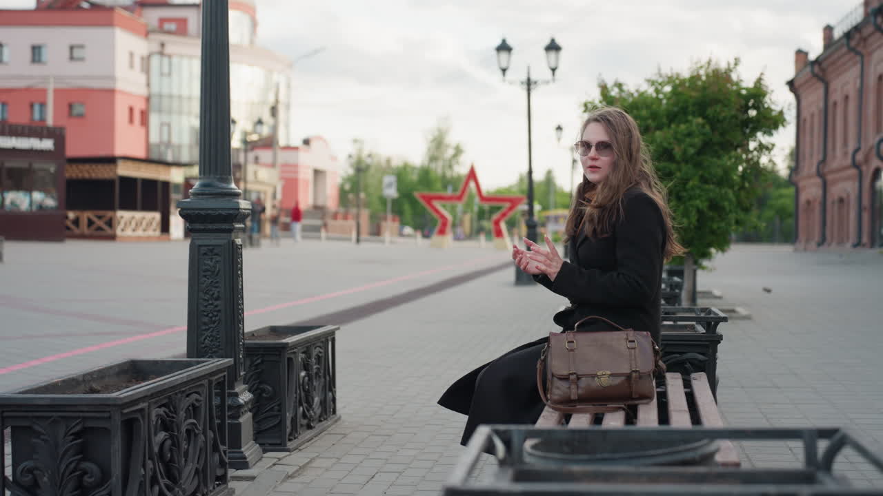 Man in glasses quickly grabs girlfriend phone and zooms off from city bench under daylight, capturing moment of sudden reaction and urban interaction surrounded by lamps, and calm street setting