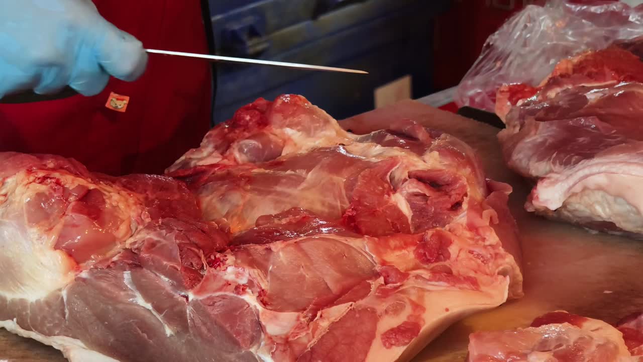 macellaio che taglia carne di maiale cruda