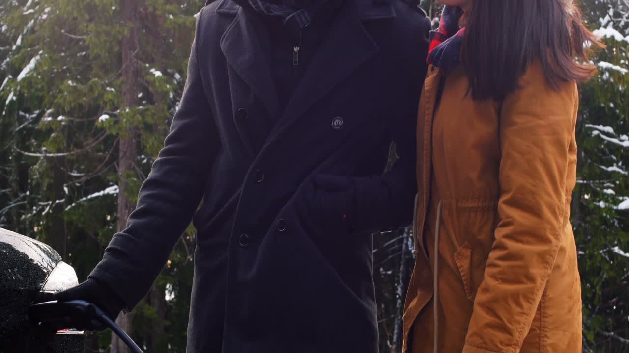 부부는 눈이 내리는 날 전기차를 충전하고 있다.