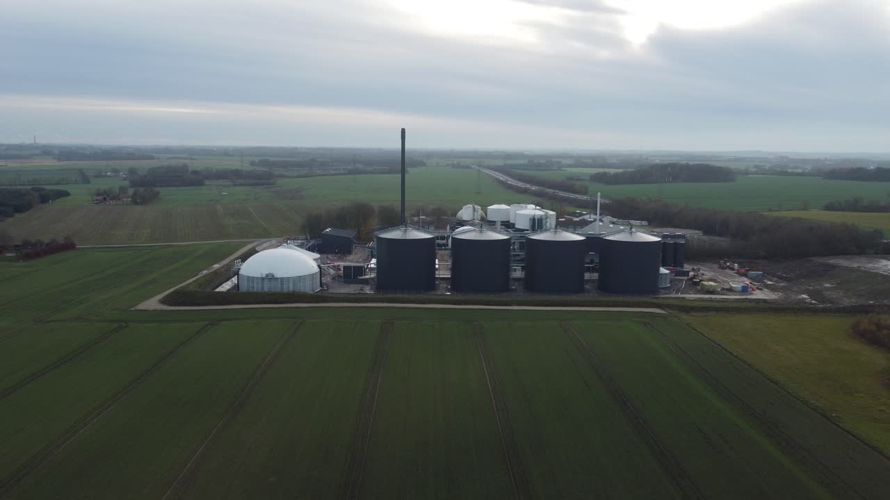 Drone orbit shot around a biogas plant in rural Denmark, showcasing renewable energy production and modern agricultural infrastructure