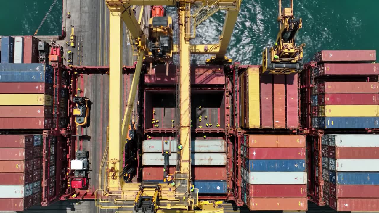 Aerial View of Container Loading Operations in a Busy Port: Overhead Shot of Cranes and Colorful Shipping Containers Being Moved by Heavy Machinery