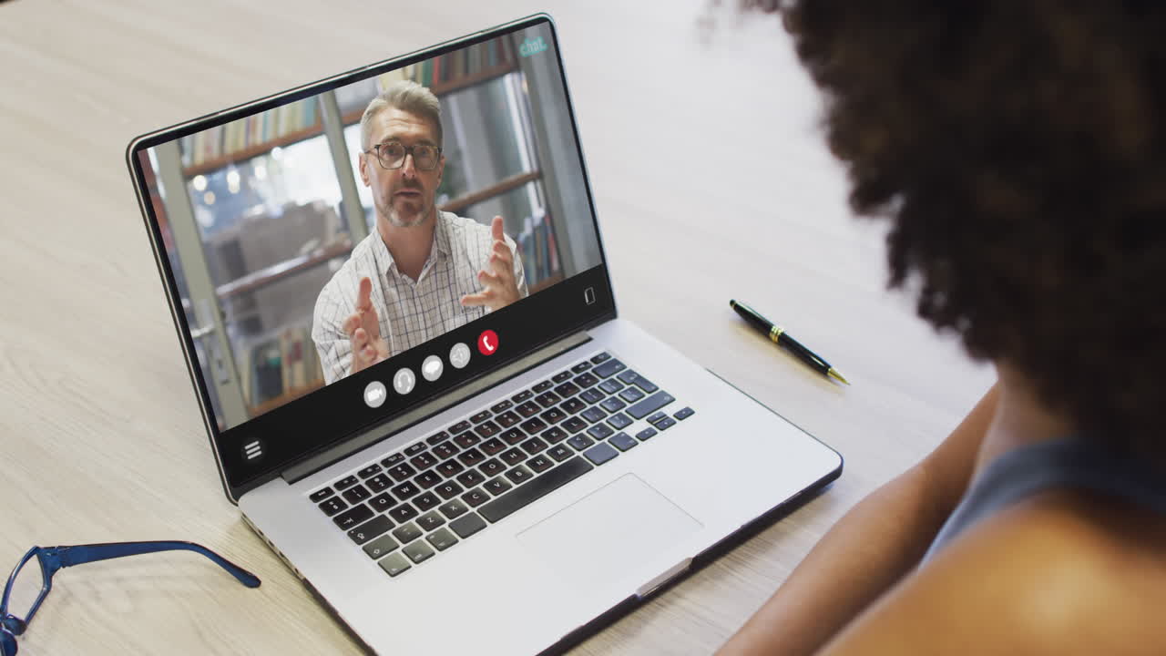 mujer afroamericana usando una computadora portátil para una llamada de video, con un colega de negocios en la pantalla