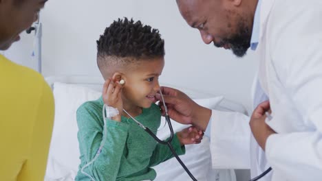 Médico-Varón-Afroamericano-Examinando-A-Un-Paciente-Infantil,-Usando-Estetoscopio-En-El-Hospital