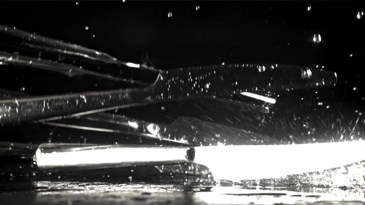 Slow Motion Knives Falling and Splashing Water on a Dark Surface