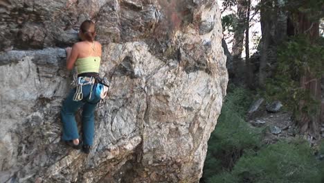 mediumshot of a rockclimber making her way up a granite cliff face