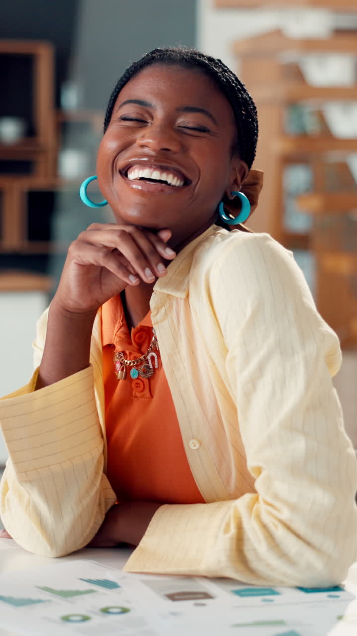 Giovane donna afroamericana che sorride e ride alla scrivania.