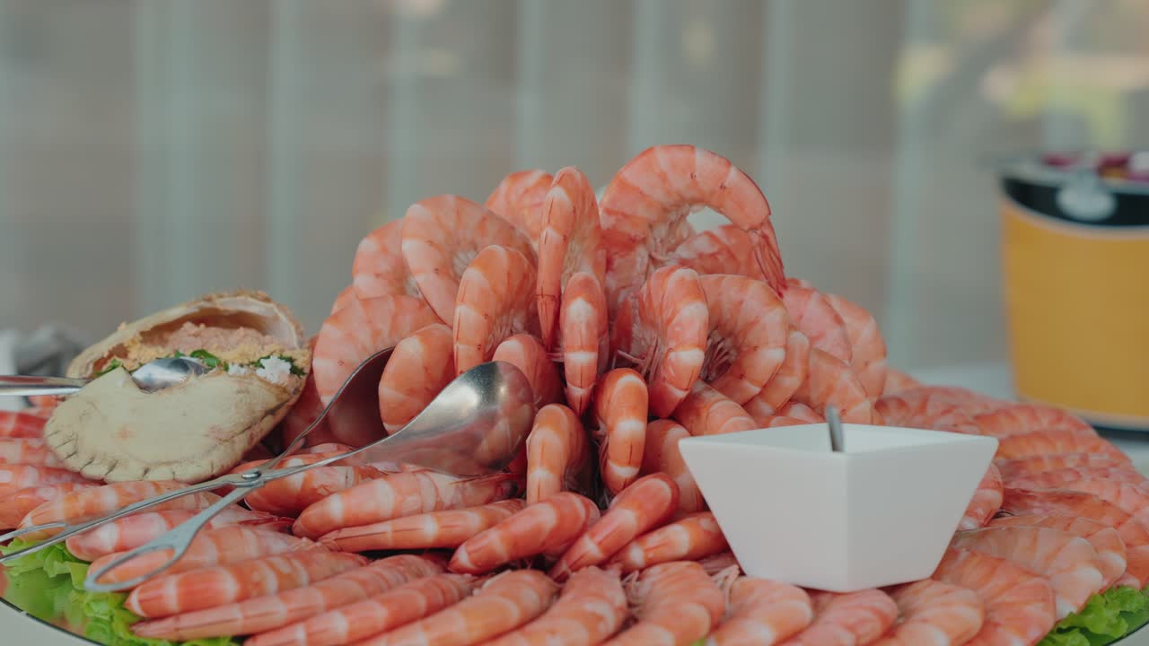 Gambas dispuestas en círculo alrededor de un cangrejo relleno servido con salsa en una bandeja fría