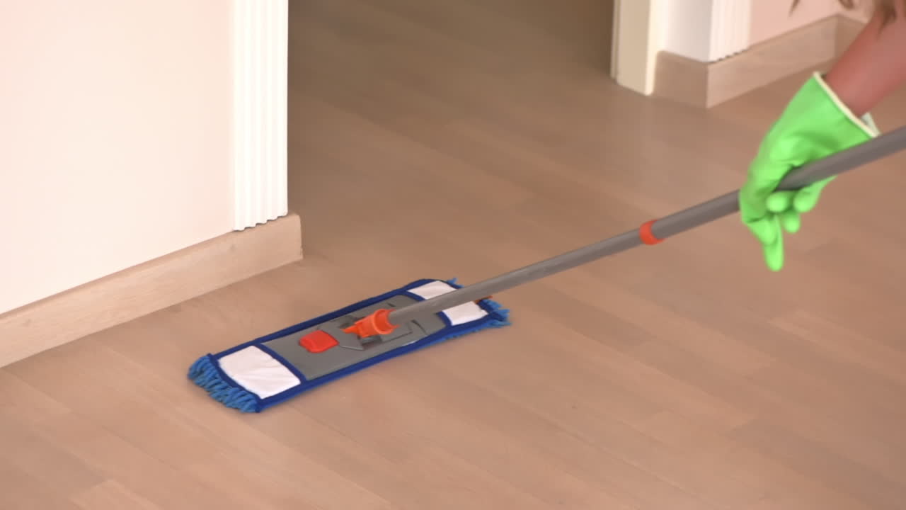 Close-up of a woman cleanind the floors with a blue mop