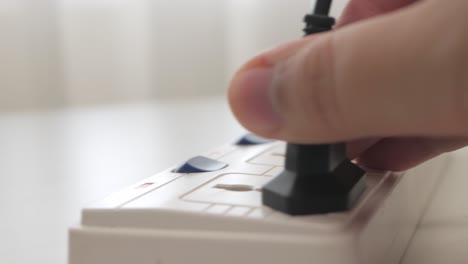 cerrar la mano masculina enchufando un cable de alimentación en la mesa