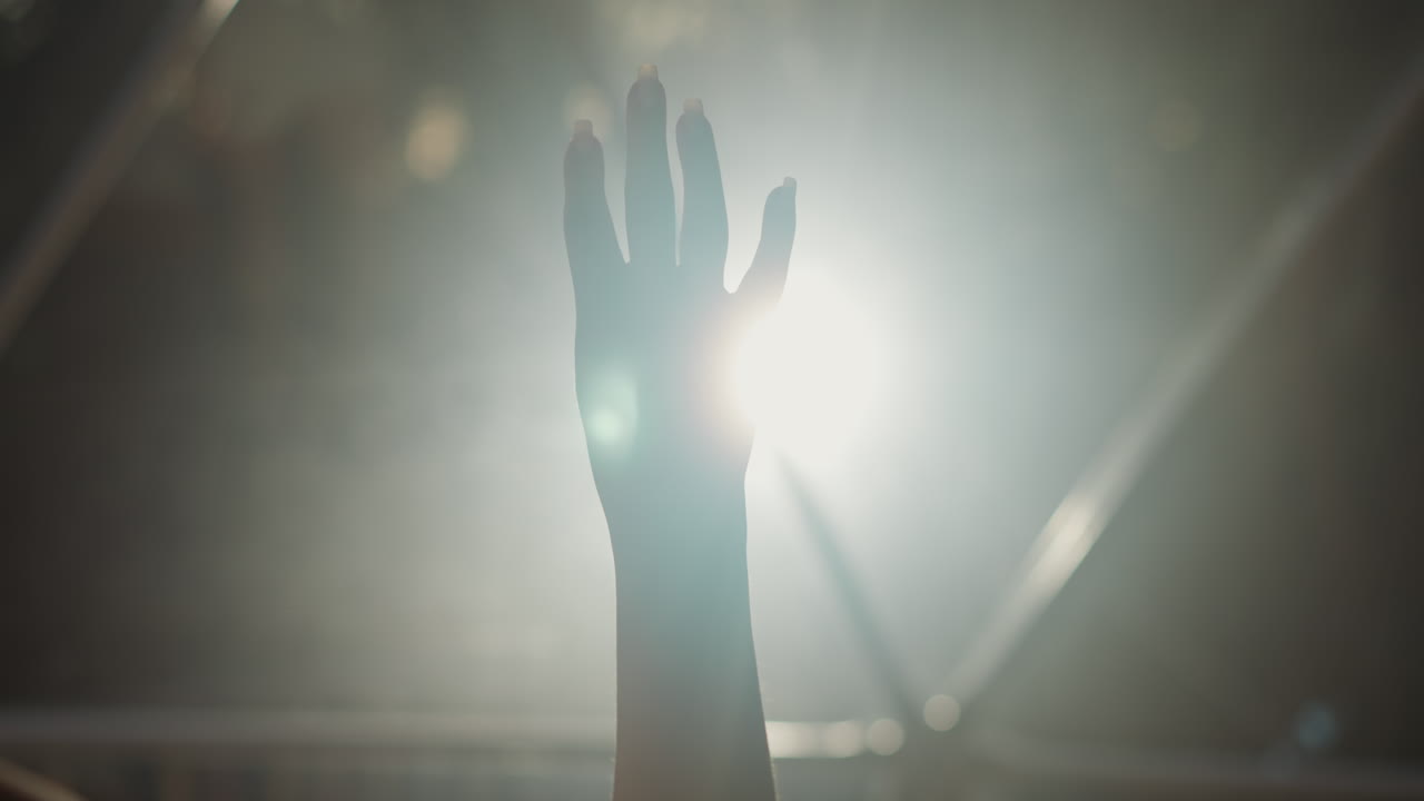 mujer puño juega silueta en luz de fondo primer plano. dama mano demuestra gesto de protesta contra la lámpara brillante en la oscuridad. símbolo del movimiento de activismo