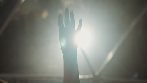 mujer puño juega silueta en luz de fondo primer plano. dama mano demuestra gesto de protesta contra la lámpara brillante en la oscuridad. símbolo del movimiento de activismo