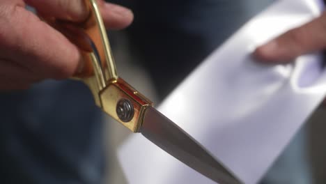 cutting a white ribbon with golden scissors at an opening event in 4k