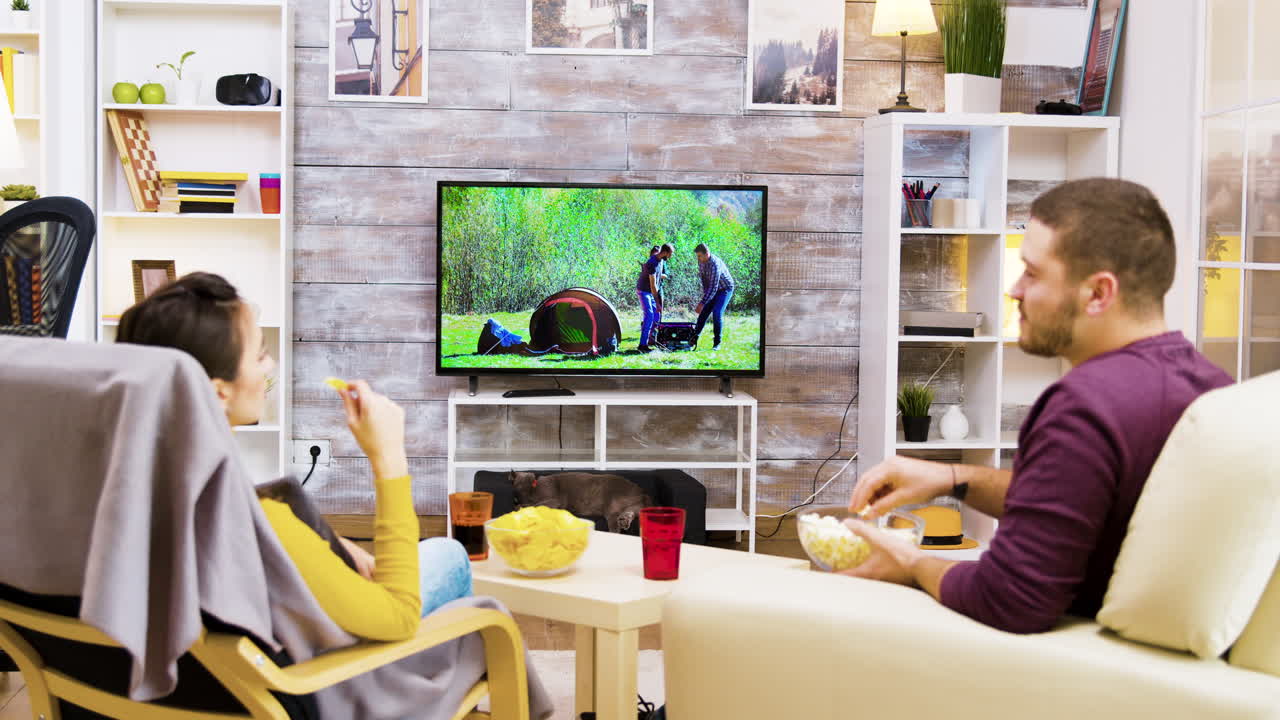 una pareja viendo la televisión en la sala de estar.