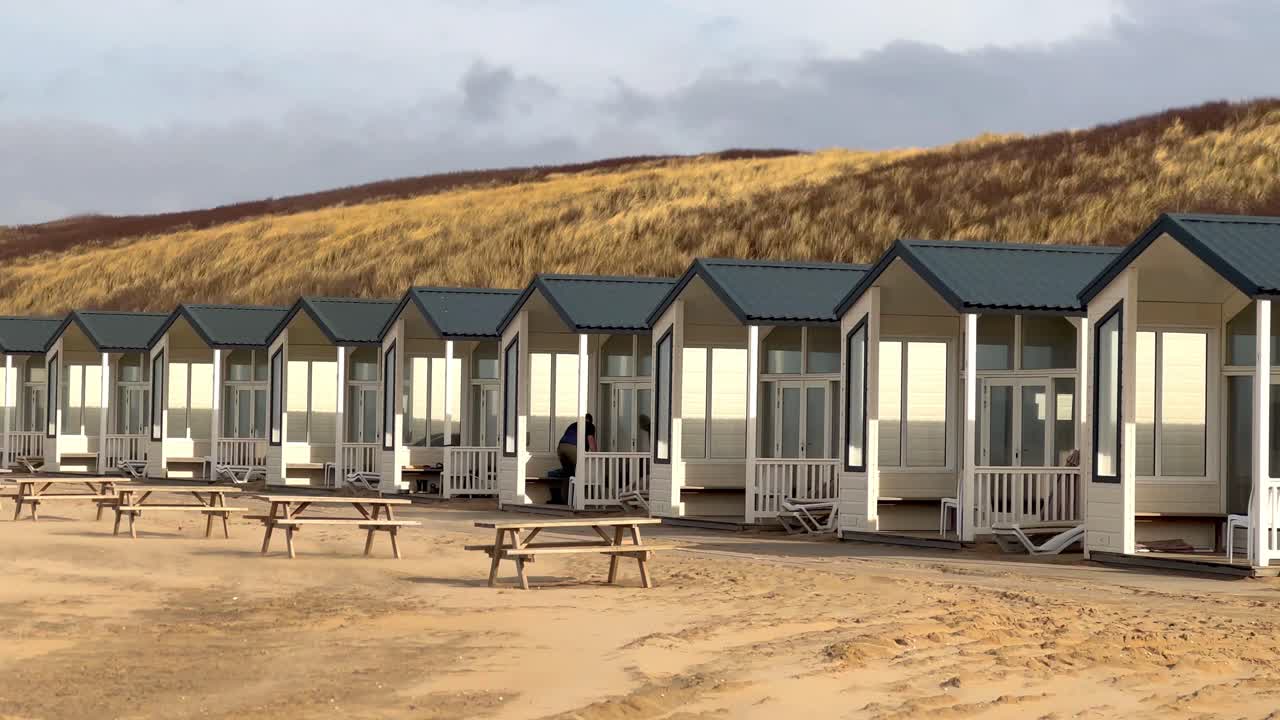 toma panorámica de hermosos apartamentos en la playa de arena de katwjik frente a las dunas al atardecer, países bajos