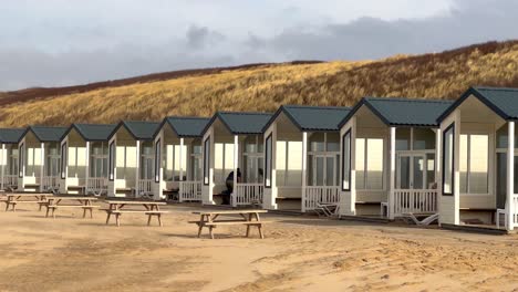 Panning-shot-of-beautiful-beach-house-apartments-on-sandy-beach-of-Katwjik-in-front-of-dunes-at-sunset,Netherlands