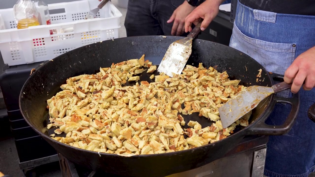 Primo piano di chef che preparano il Kaiserschmarrn, tradizionale frittata dolce sminuzzata austriaca, in una grande padella, cibo da strada e cultura
