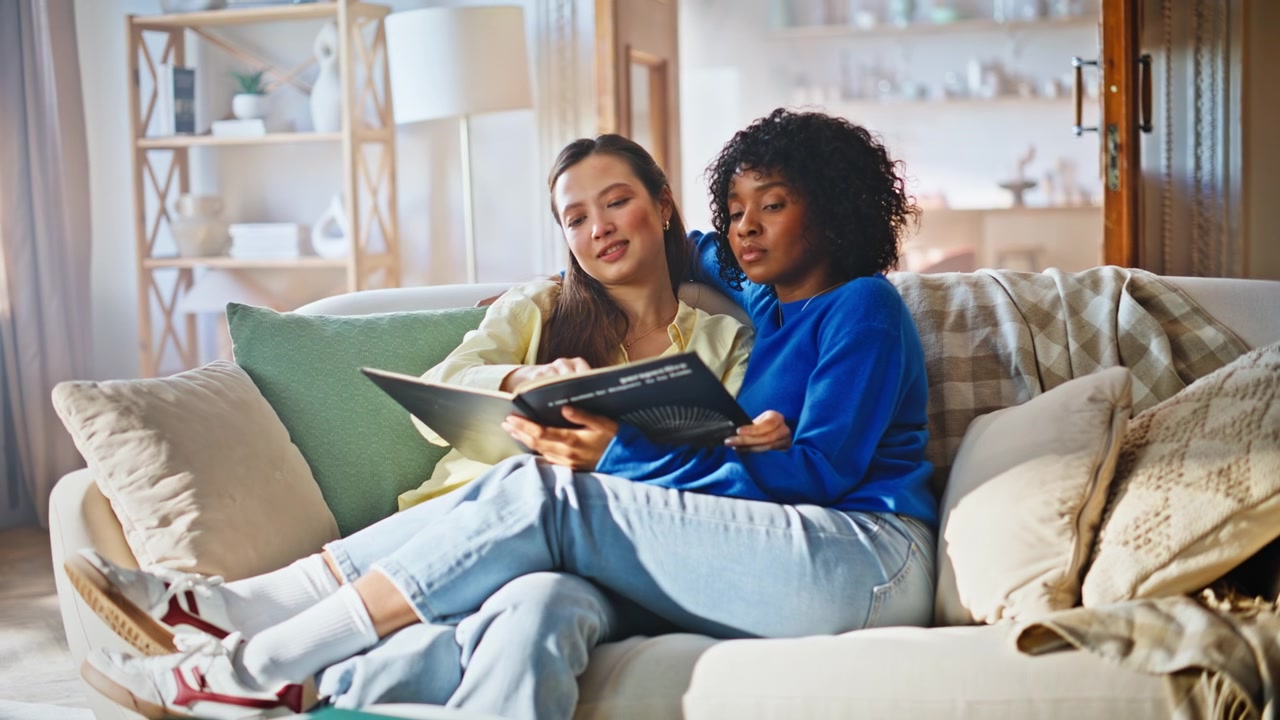 Pareja de mujeres leyendo un libro juntas en el sofá. Estilo de vida de fin de semana acogedor en casa