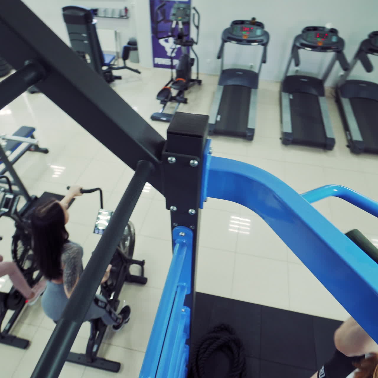 Healthy female bodybuilder doing tightening on a crossbar on the gym background. Modern sports center and women training on simulators.