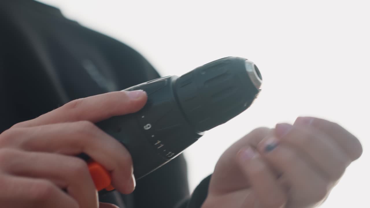 Silhouette of hands controlling drill meticulously. Backlit scene of fingers adjusting drill with precision. Concentrated workshop environment with detailed grip and controlled trigger actions