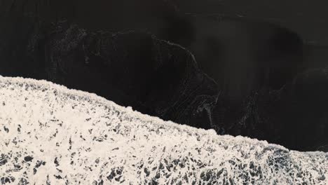 Waves-Crash-on-Black-Sand-Beach-Shore---Top-Down-Aerial-Long-Shot