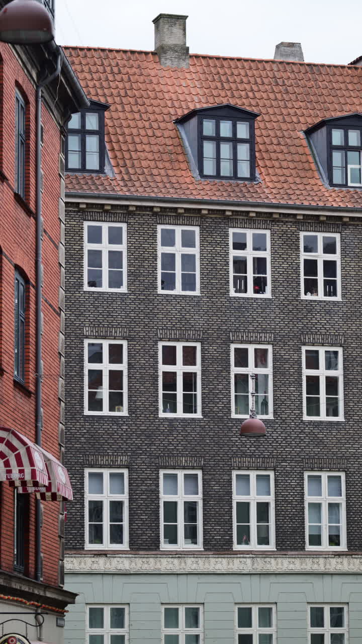 Esterno di storico edificio in mattoni con molte finestre e tetto classico, che illustra l'architettura urbana. Copenaghen, Danimarca