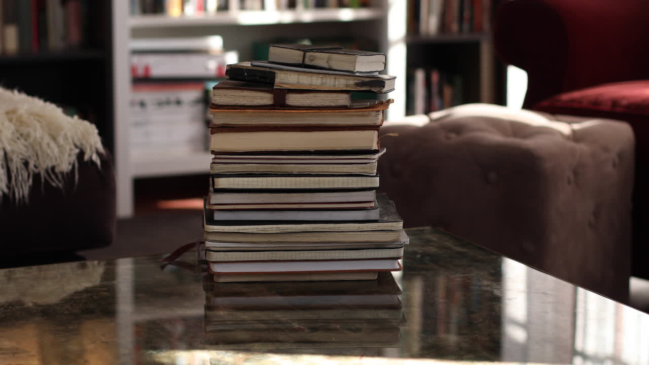 Handheld shot of stack of old notebooks on coffee table