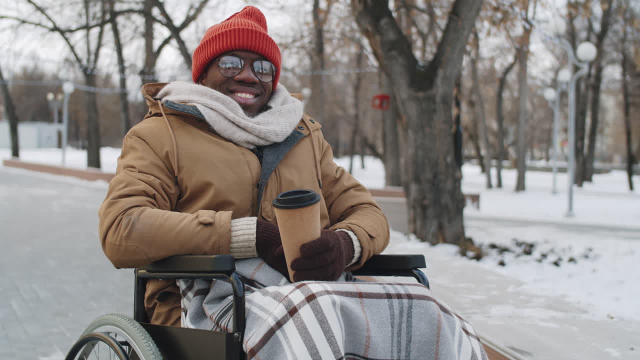hombre en silla de ruedas disfrutando de café en el parque de invierno