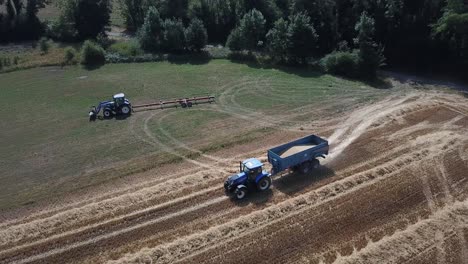 Eine-Filmische-4K-Drohnenaufnahme-Von-Zwei-Traktoren-Bei-Der-Arbeit-Auf-Einem-Feld-In-Frankreich,-Die-Die-Landwirtschaft-Mit-Epischer-Aussicht-Und-Dramatischem-Staub-Zeigt