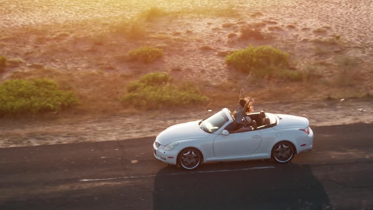 Amici che si godono un road trip al tramonto in una decappottabile