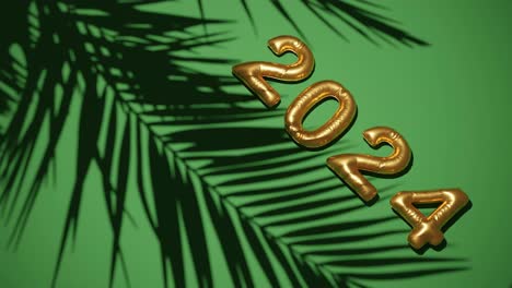 golden ballon 2024 on silhouetted palms green  background