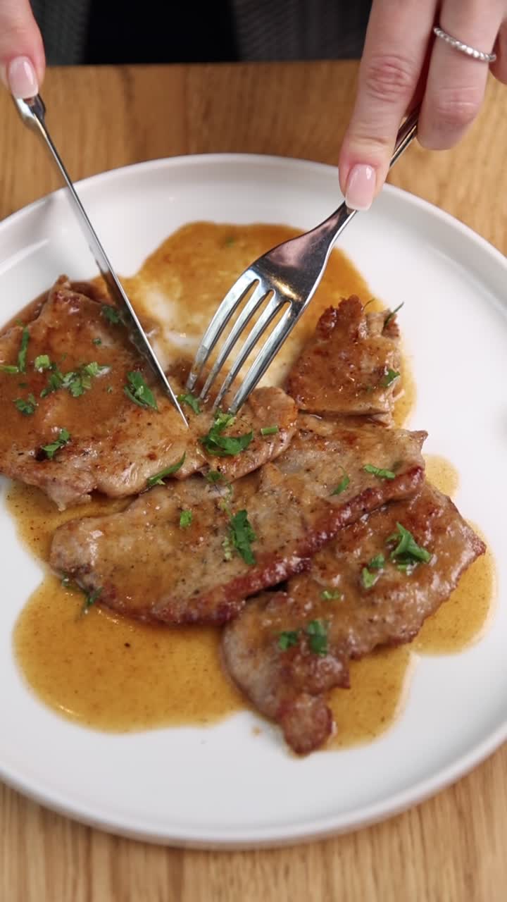 Primo piano di persona che taglia deliziose scaloppine di carne con salsa