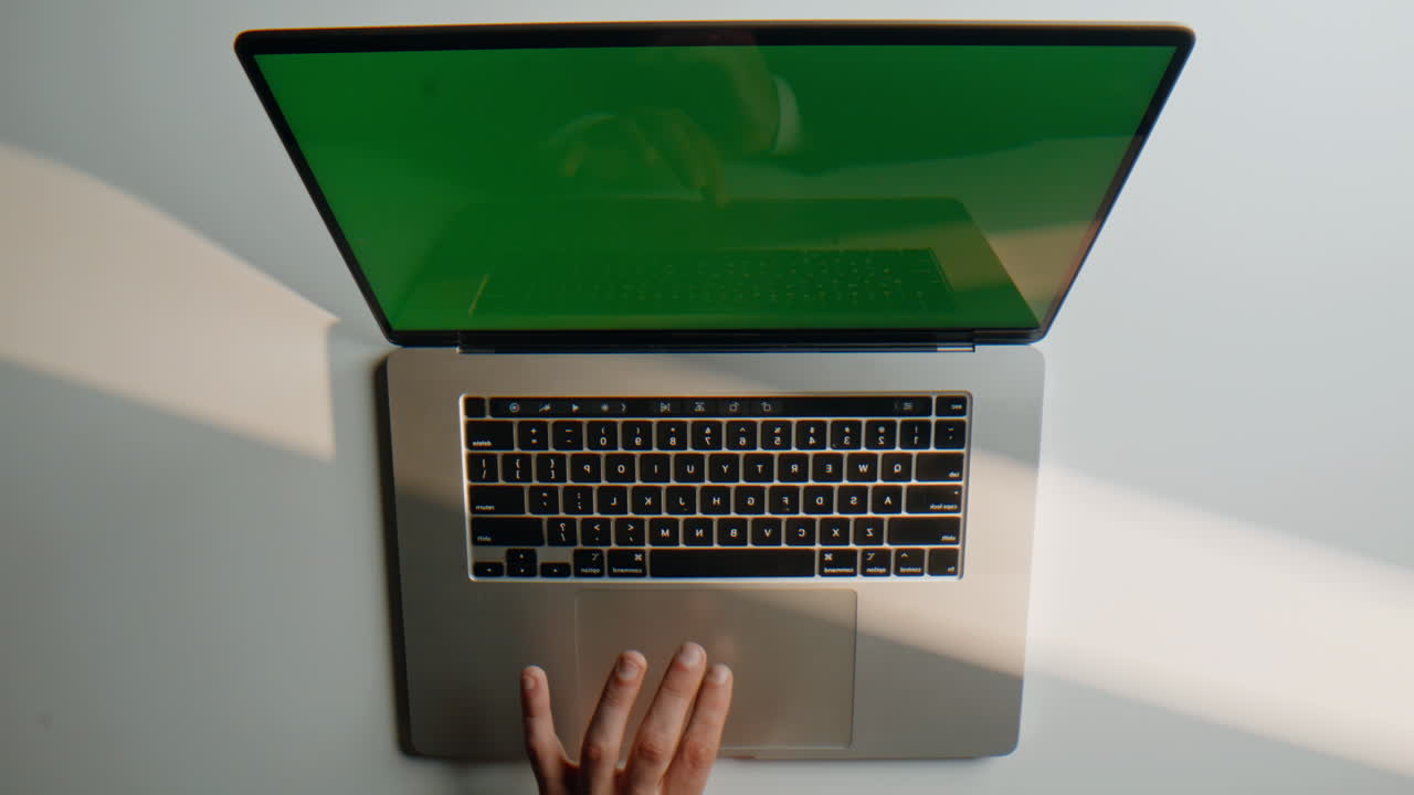 Hands typing chromakey laptop in organized modern desk workspace overhead view