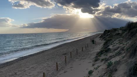 sun rays, punching through clouds on a sunset by the beach