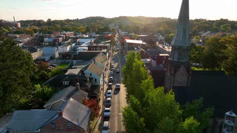 aerial pullback reveals church steeple and old homes along quiet street in usa