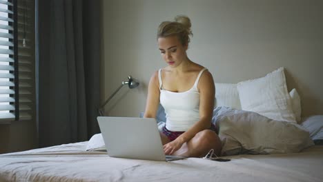 charming woman using laptop on bed