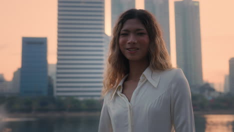 a woman standing in front of a city skyline at sunset