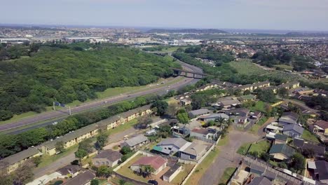 Luftaufnahmen-Einer-Drohne,-Die-über-Wohnhäuser-Mit-Blick-Auf-Eine-Viel-Befahrene-Autobahn-Mit-Fließendem-Verkehr-In-Einem-Vorort-Von-Yellow-Wood-Park-Durban-Fliegt