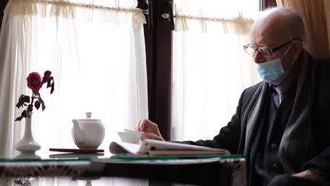 elderly man wearing a face mask having tea