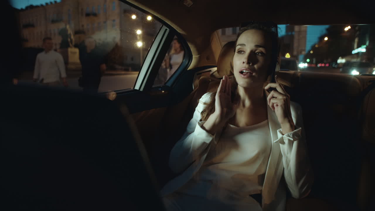 Empresaria seria hablando por smartphone en un coche de negocios. Mujer trabajando horas extras.