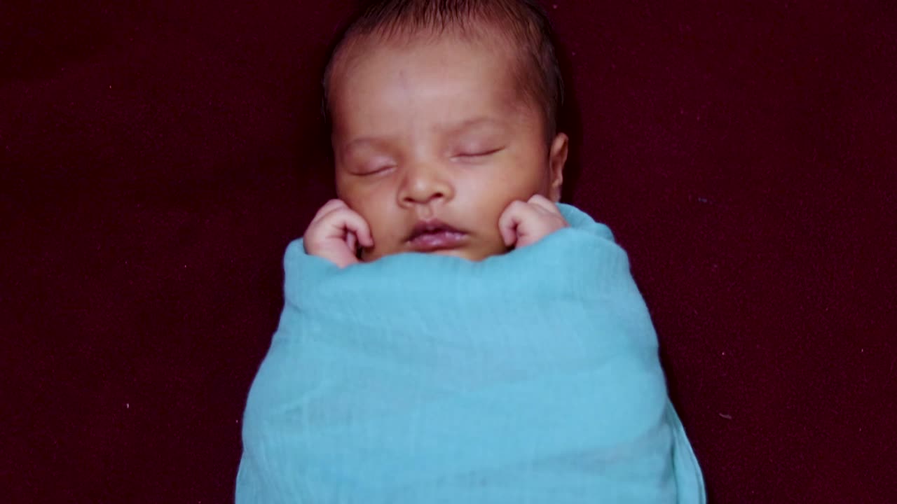 carino neonato che dorme in un involucro per bambini scattato dall'angolo superiore