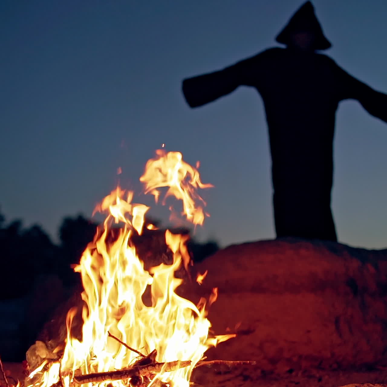 Old evil witch conjures in the wizarding lair. Scary Halloween concept. Burning fire.