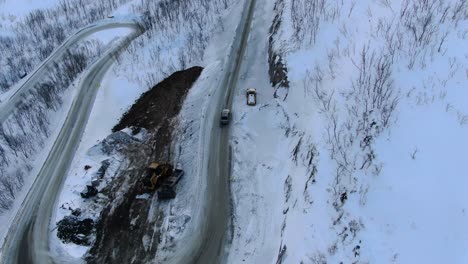 Drohnenansicht-Der-Tromsø-Berge-Im-Winter-Voller-Schnee,-Die-Eine-Schlangenstraße-Zeigt,-Die-Einem-Auto-Von-Oben-Folgt,-Das-Durch-Einen-Wald-Fährt