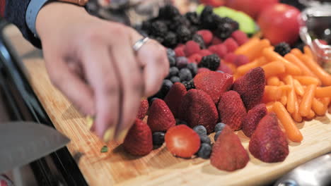 high angle close up of woman carefully cutting tops off fresh strawberries