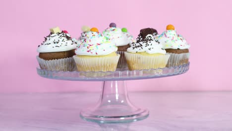 putting crystal plate with delicious cup cakes with cream and crumbs for party