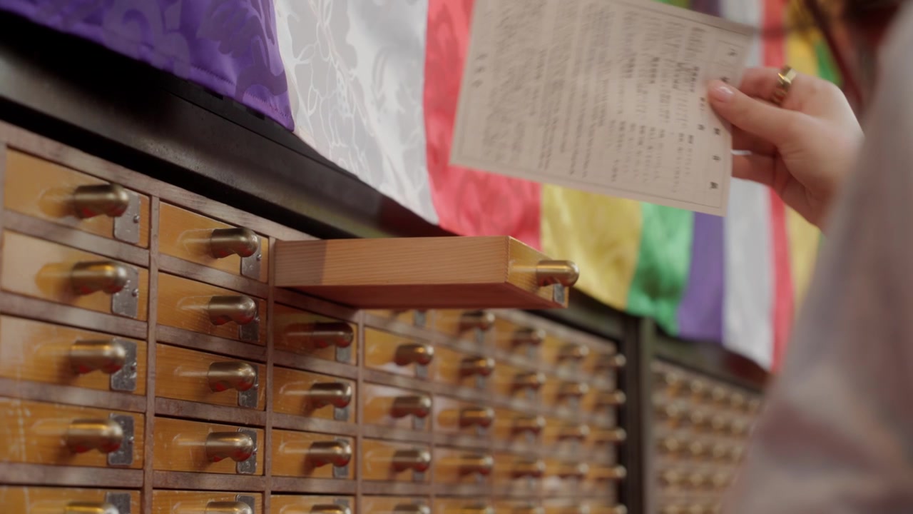 Close view of woman opening omikuji drawer inside Japanese temple in Tokyo