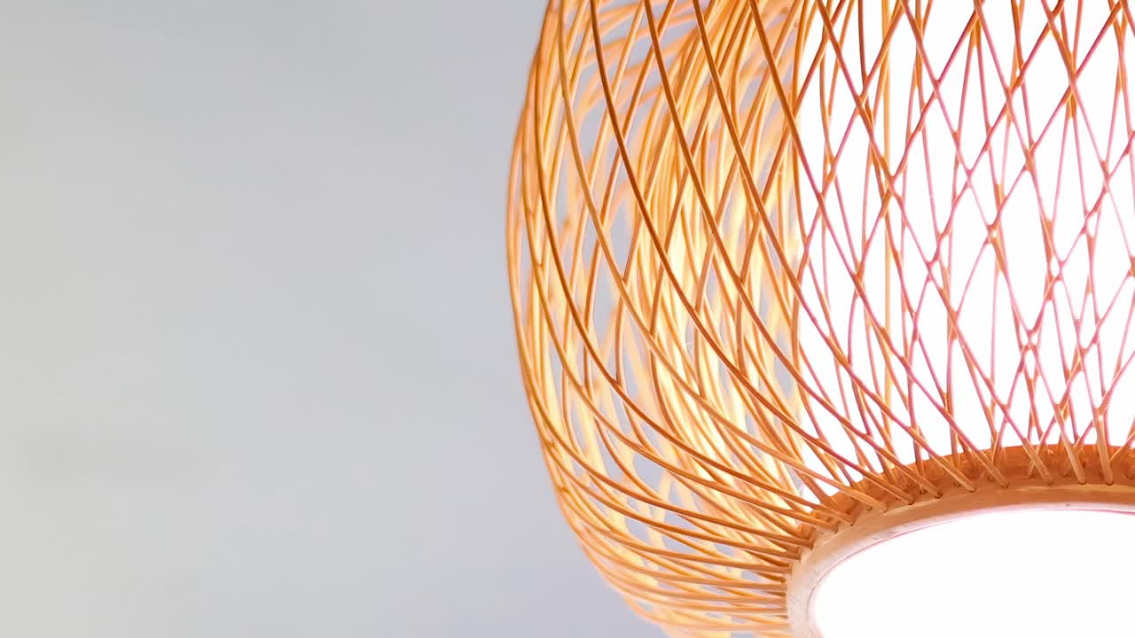 Detailed view of intricately woven bamboo lanterns with warm light against a neutral background.